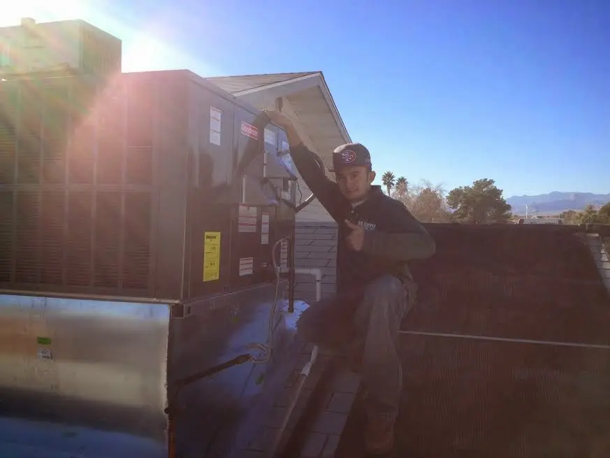 HVAC technician performing Air Duct Repair on a rooftop unit in Woodbury